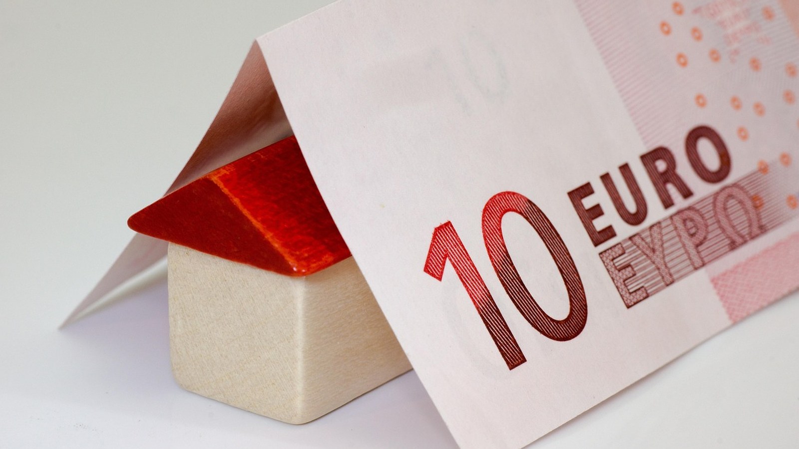 Maison en bois et billet de 10 euros symbolisant l'apport personnel pour un crédit immobilier