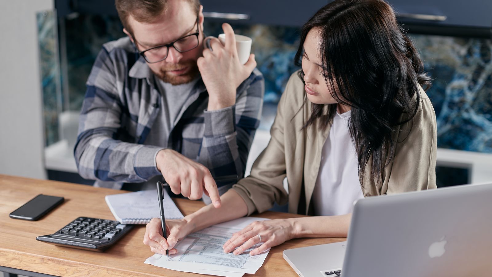 Un couple examine son tableau d'amortissement de crédit immobilier avec calculatrice et ordinateur